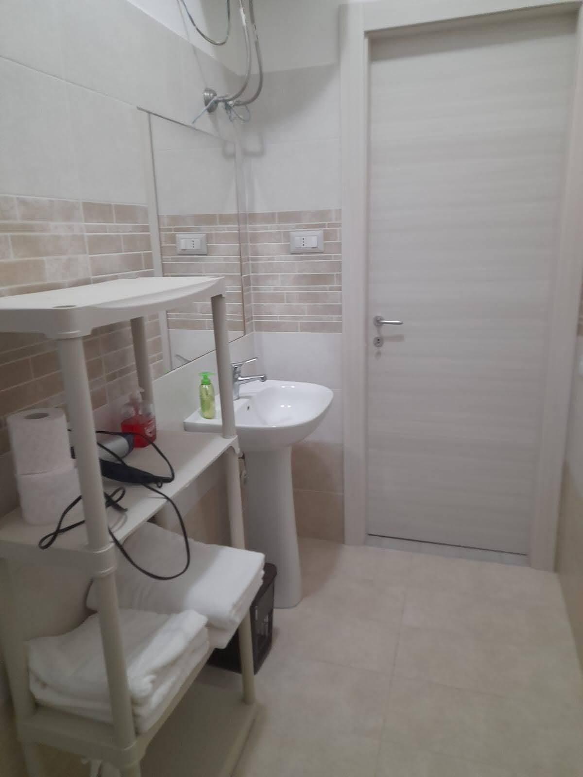 A bathroom with a white sink, a mirror, and a towel rack.