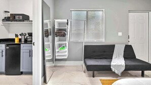 A compact living space with a kitchenette, a sofa, and a built-in shelving unit. - Cozy Studio in Miami Near Wynwood Prime Location (Miami)