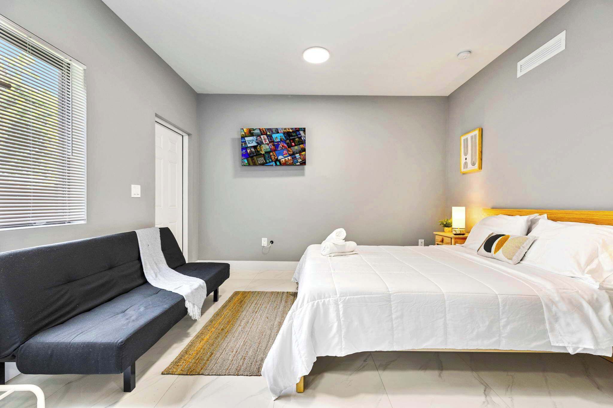 Een moderne slaapkamer met een bed, een bank, een vloerkleed en een kunstwerk aan de muur.