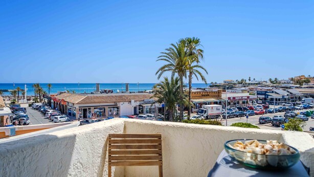 Un balcón con vistas a una calle concurrida y la playa.