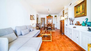 Una sala de estar con sofá, una mesa de comedor con sillas y un aparador con adornos.
