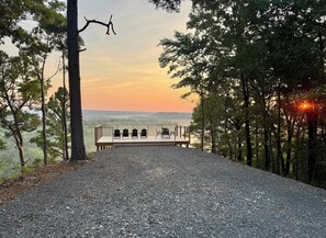 A gravel path leading to a wooden deck with outdoor seating, surrounded by trees and overlooking a landscape. - Redbud-a magical camping experience (Tahlequah)