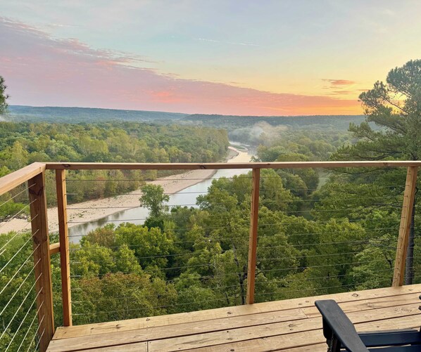 A wooden deck with a view of a river and forest.
