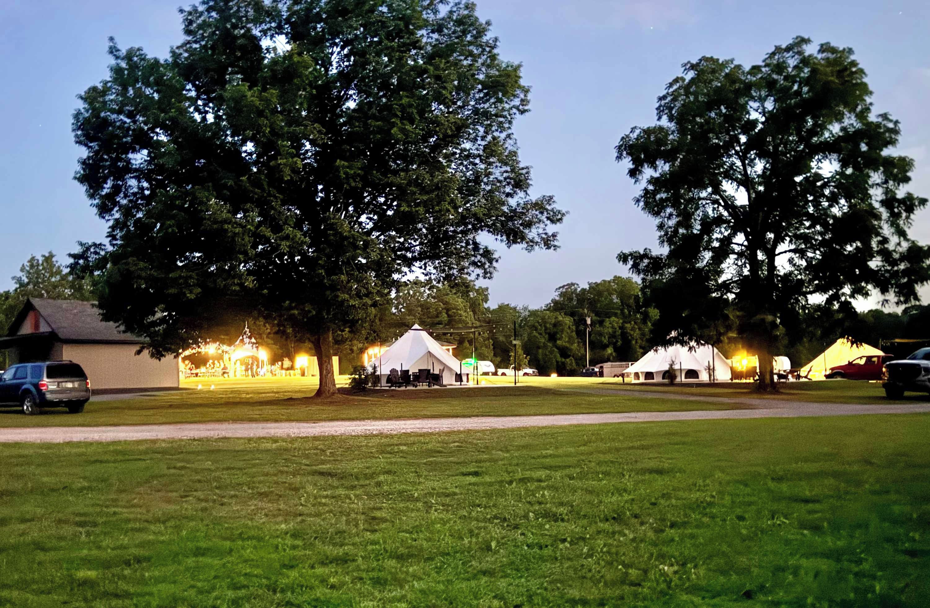 Une zone herbeuse avec des tentes et un bâtiment, probablement un terrain de camping ou un parc.