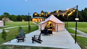 Una carpa con zona de comedor, un brasero y asientos al aire libre.