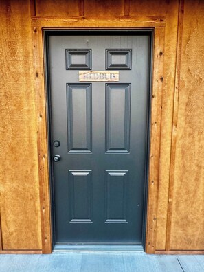 A dark wooden door with a sign above it reading "REDBUD". - Redbud-a magical camping experience (Tahlequah)