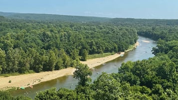 Ein Fluss, umgeben von dichtem Wald, mit Booten und Menschen auf dem Wasser.