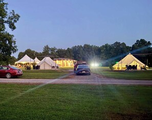 Un terrain de camping avec des tentes et une voiture garée sur un chemin de terre.