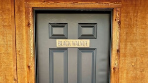 Una puerta negra con un letrero que dice "BLACK WALNUT" encima, enmarcada por paneles de madera.
