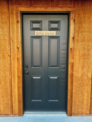 Une porte noire sur laquelle est apposée une plaque portant l’inscription « BLACK WALNUT », le tout encadré de panneaux en bois.