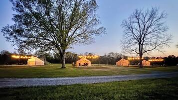 Ein Campingplatz mit Zelten und Lichterketten, umgeben von Bäumen und Gras.