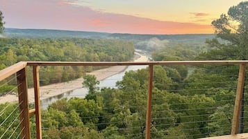 A wooden deck with a view of a river and forest.