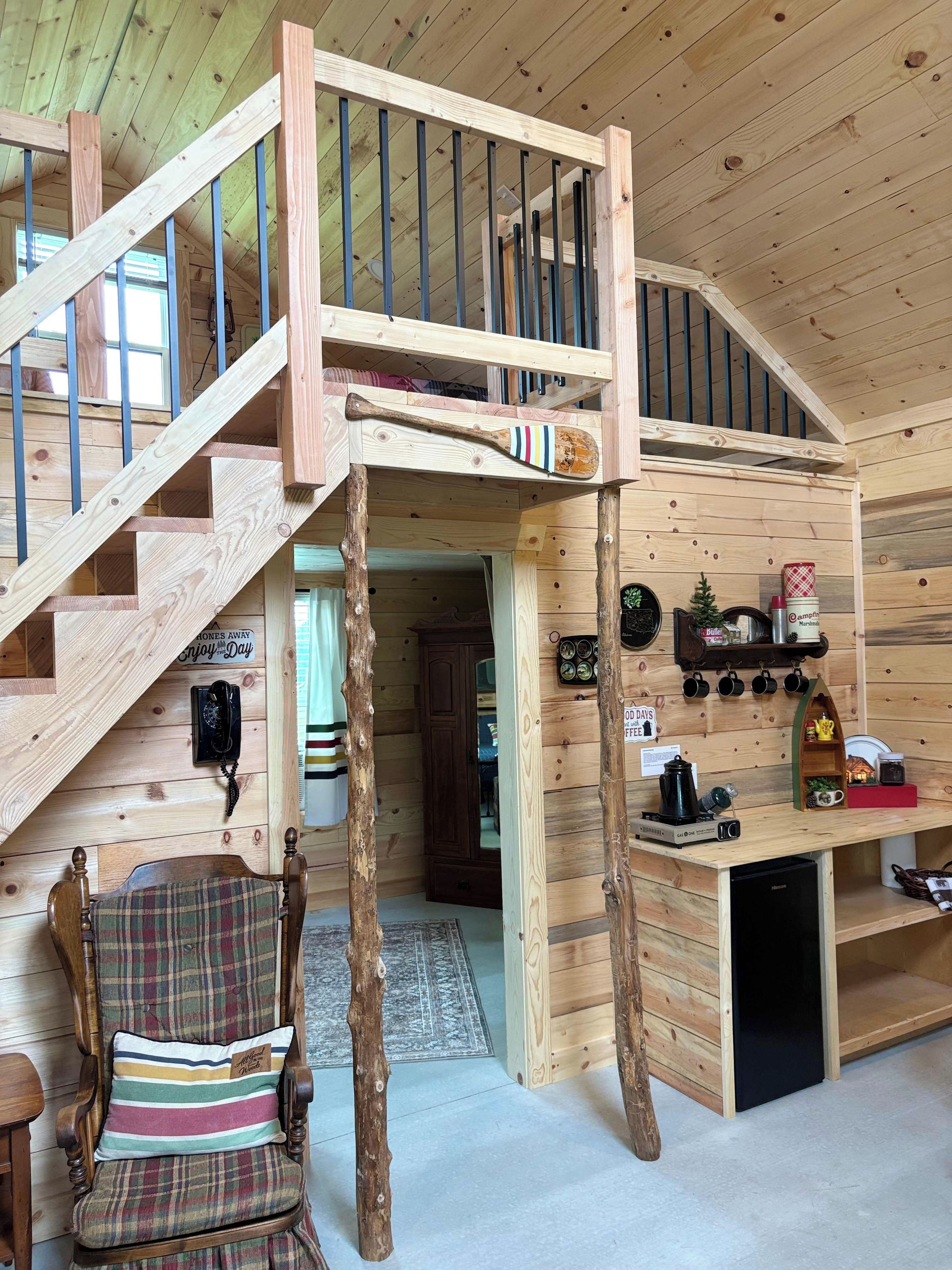 Ein Holzinnenraum mit einer Treppe, einem Karokissen und einem Couchtisch mit diversen Gegenständen.