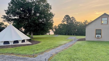 A grassy area with a tent, a pathway, and a building.