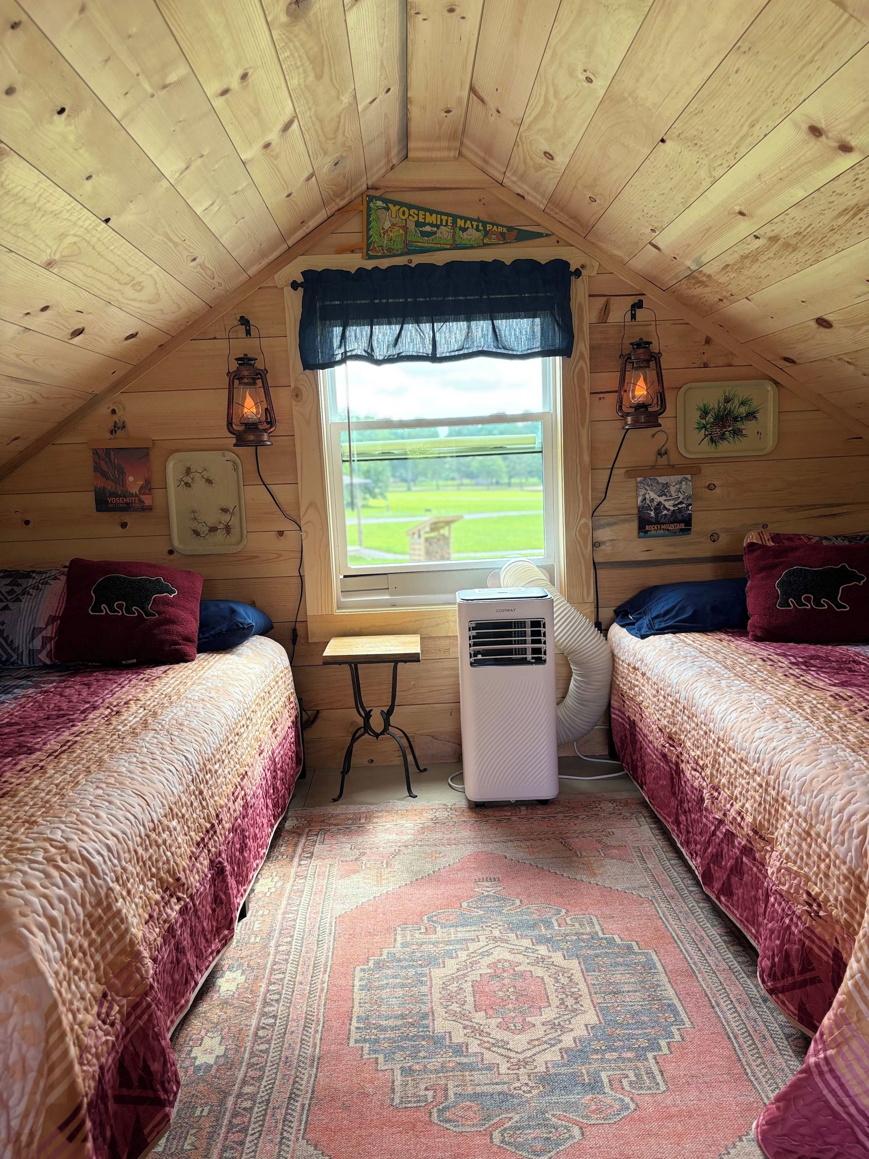 Ein gemütliches Schlafzimmer im Dachgeschoss mit zwei Betten, einem Fenster, einer Heizung und rustikalen Einrichtungsgegenständen.