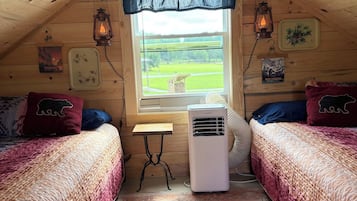 Ein gemütliches Schlafzimmer im Dachgeschoss mit zwei Betten, einem Fenster, einer Heizung und rustikalen Einrichtungsgegenständen.