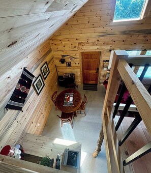 A wooden interior with a dining area, a door leading to another room, and a window with a view.