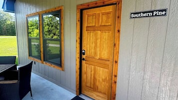 Eine Holztür mit einer schwarzen Fußmatte, einem Fenster und einem Schild mit der Aufschrift 'Southern Pine'.