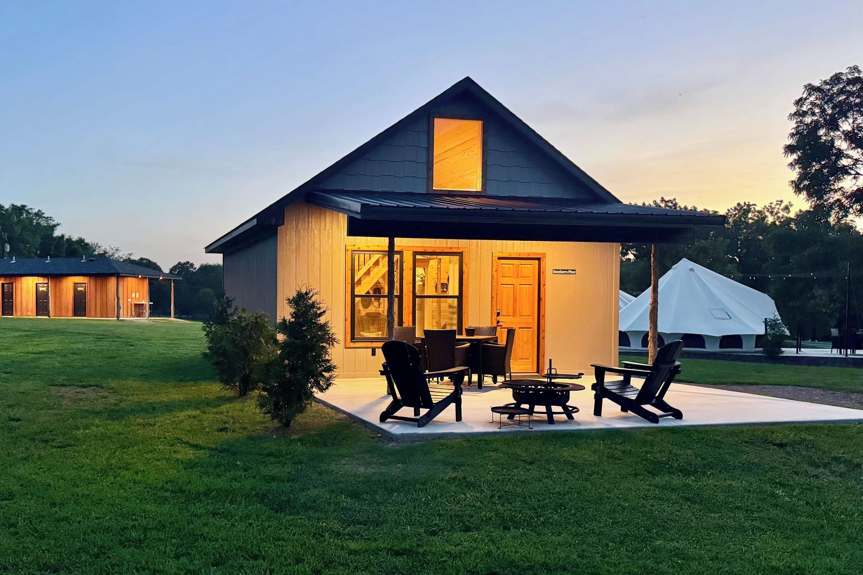 A small house with a covered patio, a dining table, and outdoor seating.