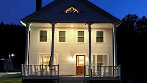 A two-story house with a front porch, a central entrance, and a small front yard. - Downtown Ludlow, walk to ski shuttle, room for multiple families, pet friendly! (Ludlow)