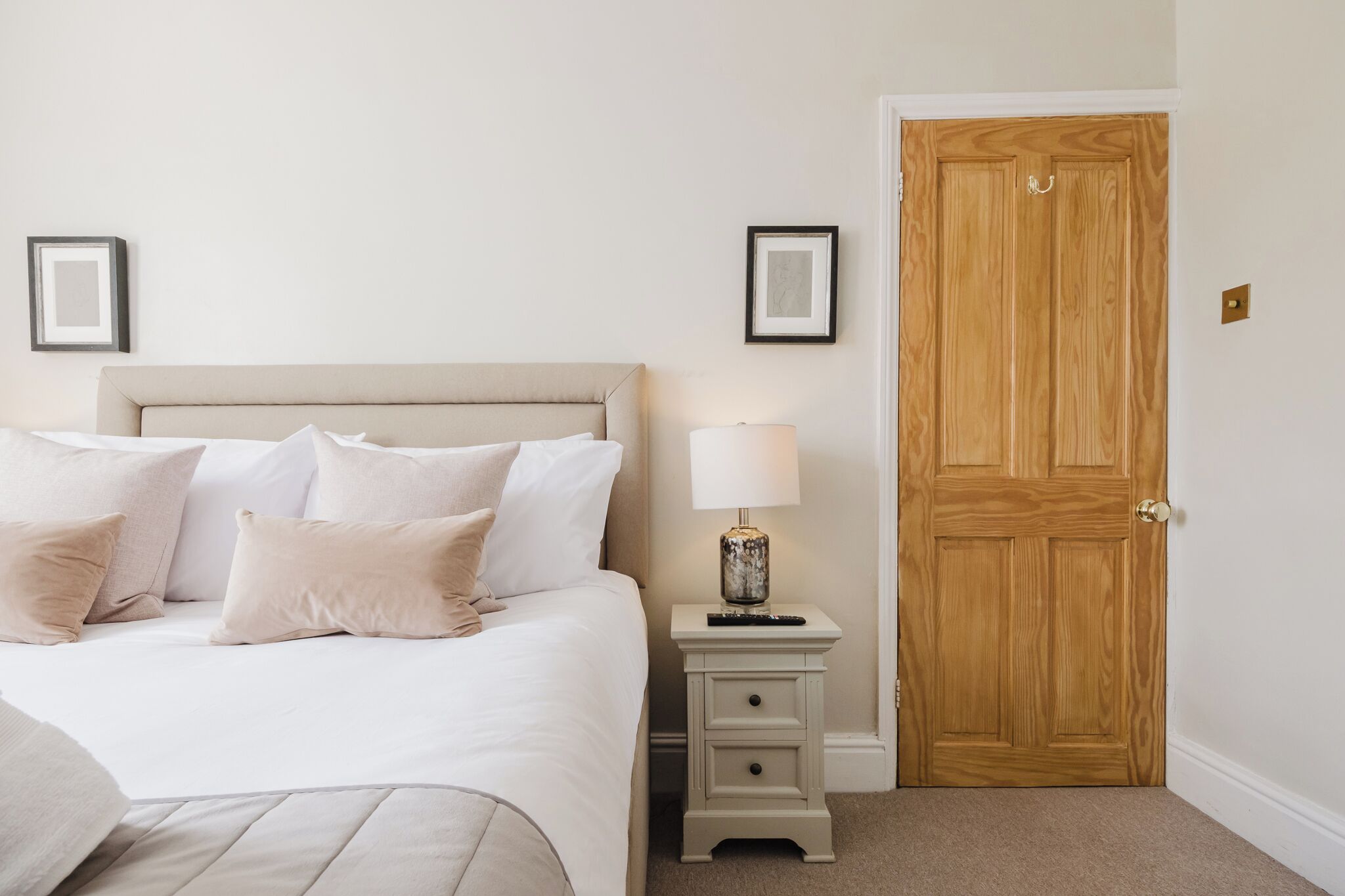 Une chambre à coucher avec un lit, une table de chevet, une lampe et une porte en bois.