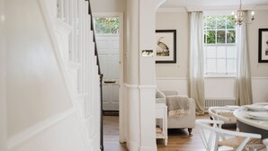 A spacious room with a wooden floor, white walls, and a white door. There is a white chair and a table with chairs. - Gorgeous House - Garden & Open Living (Cheltenham)