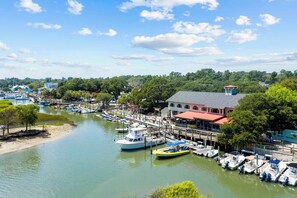 A marina with boats docked, a building with a red roof, and a dock extending into the water. - High Tides, Good Vibes Resort Pool By Beach Star (Murrells Inlet)