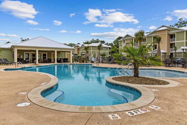 A swimming pool with a no step zone, lounge chairs, and a covered seating area.