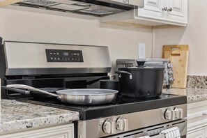 A kitchen with a stainless steel stove, a digital display, and a granite countertop.