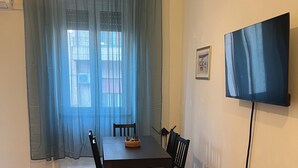 Un comedor con una mesa de madera, sillas, un televisor en la pared y una planta.