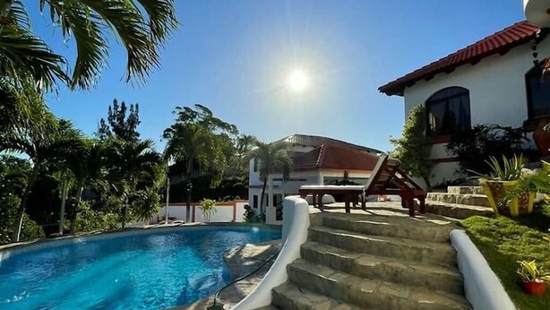 Una piscina con escalones de piedra que conducen a un edificio con techo rojo.