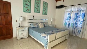 Un dormitorio con cama, mesitas de noche, ventilador de techo y una puerta.