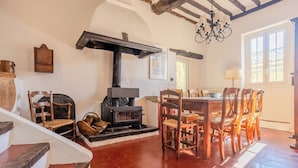 Una habitación rústica con chimenea, sillas de madera, una mesa de comedor y una escalera.
