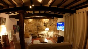 Una habitación acogedora con pared de piedra, una cama, un escritorio y un televisor.