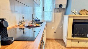 Une cuisine moderne dotée d’une plaque de cuisson à induction noire, d’un four encastré et d’une fenêtre située au-dessus de l’évier.