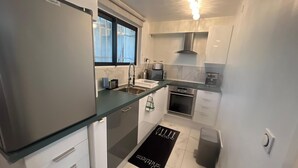 Cozinha compacta com geladeira, pia, fogão e janela.