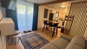 Uma sala de estar com sofá, mesa de centro, tapete e um espaço de jantar com cadeiras e mesa.
