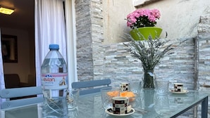 Uma mesa de vidro com uma garrafa de Evian, um vaso com lavanda e uma caneca com apoio para copo.