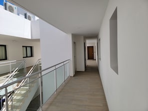 A modern interior with a glass railing, a wooden floor, and a staircase leading to an upper level.
