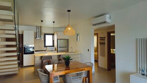 A modern kitchen with a built-in oven, microwave, and refrigerator. There is a dining area with a wooden table and wicker chairs. - 3-bedroom Penthouse with Rooftop Pool, Los Corales Beach area (Punta Cana)