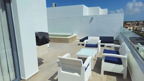 A rooftop terrace with white wicker furniture, a small table, and a built-in grill. - 3-bedroom Penthouse with Rooftop Pool, Los Corales Beach area (Punta Cana)
