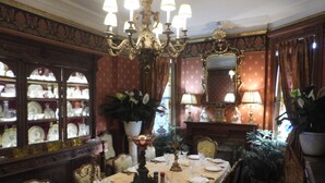 A formal dining room with a long table set for a meal, surrounded by ornate furniture and decorative elements.