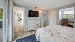 Une chambre à coucher avec un lit, une commode, une télévision et une fenêtre.