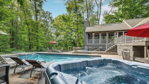 A pool area with a hot tub, lounge chairs, and a wooden deck.