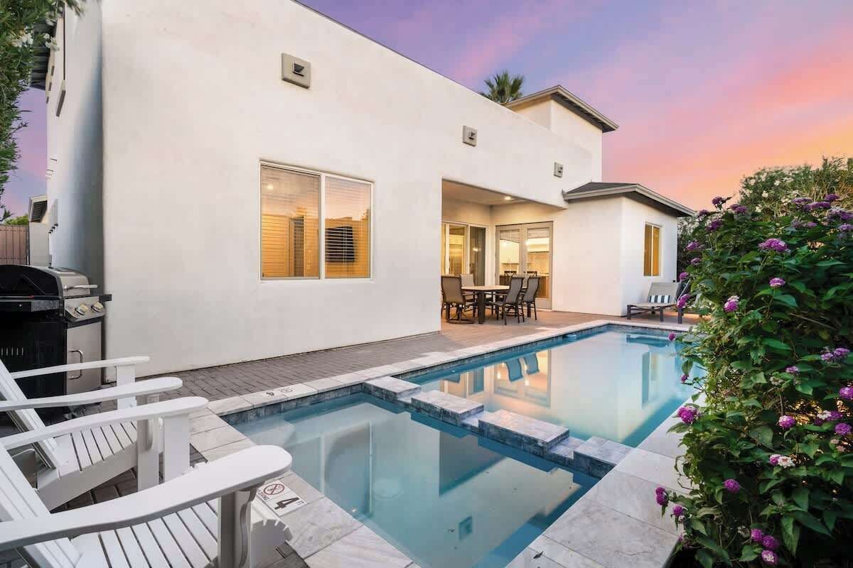 A modern house with a swimming pool, outdoor furniture, and a patio area.