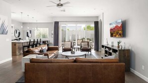 Een moderne woonkamer met een hoekbank, een eethoek en een keuken op de achtergrond.