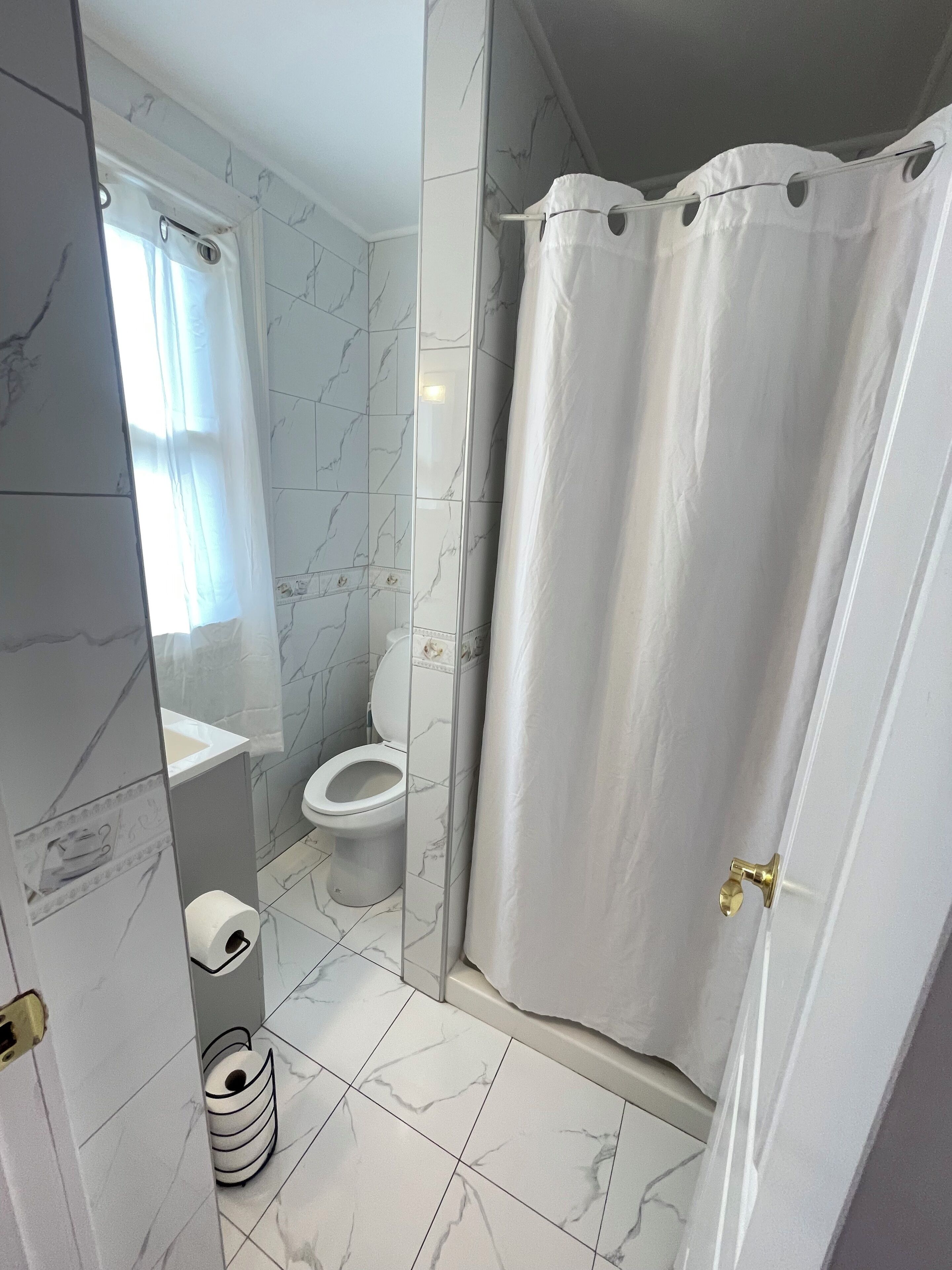 A bathroom with a toilet, sink, and shower curtain.