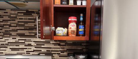 A kitchen with a stainless steel refrigerator, a coffee maker, a toaster, and a drawer organizer with utensils.