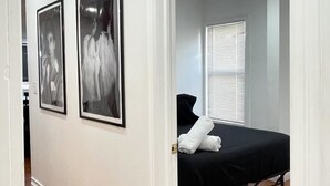 Una habitación de hotel con una cama, una puerta que da a otra habitación y dos fotografías enmarcadas en la pared.