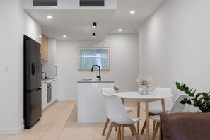 Uma cozinha moderna com ilha central, cadeiras brancas e mesa de jantar.